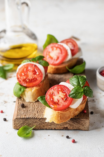 Bruschetta con pomodori, mozzarella e basilico su tavola di legno con ingredienti