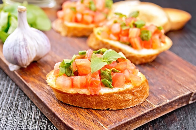 Bruschetta con pomodoro, basilico e spinaci su un piatto, olio vegetale in un decanter su fondo di legno