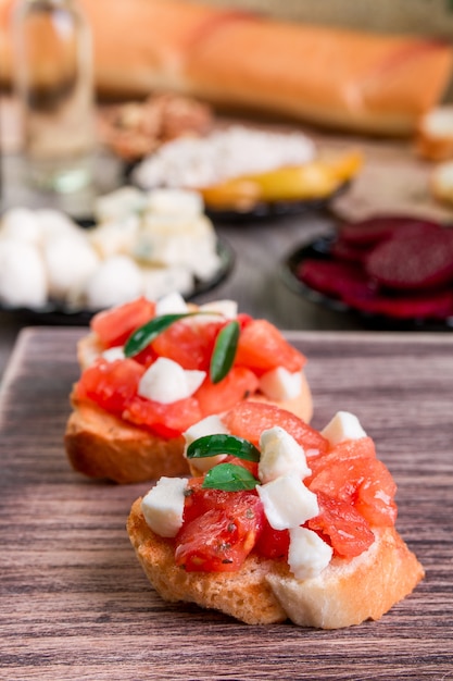 Bruschetta con pomodoro, mozzarella e basilico su fondo di legno