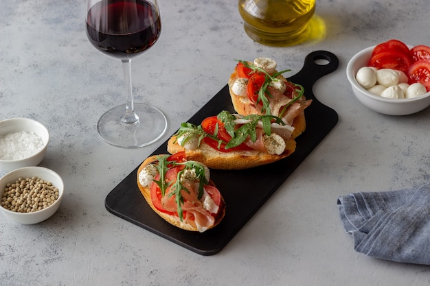 Bruschetta con prosciutto, mozzarella, pomodorini e rucola. Antipasto di vino. Merenda.