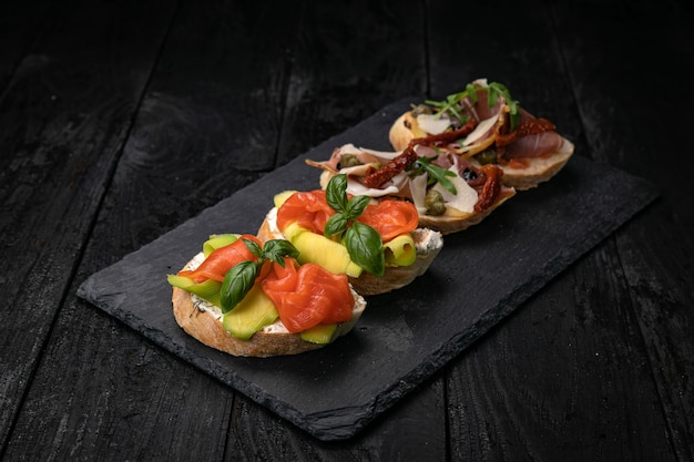 Bruschetta con salmone e carne su un tavolo di legno scuro