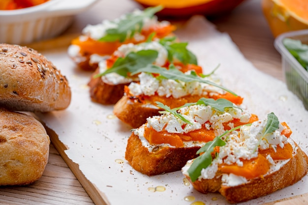 Bruschetta di ciabatta alla griglia con zucca al forno, feta rucola e spezie. sano spuntino autunnale di zucca al forno