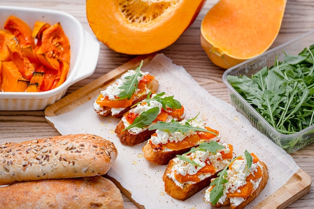 Bruschetta di ciabatta alla griglia con zucca al forno, feta rucola e spezie. sano spuntino autunnale di zucca al forno