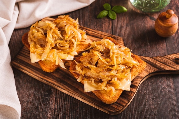 Bruschetta fatta in casa con formaggio e cipolle fritte su una tavola di legno