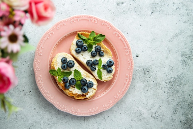 Bruschetta fatta in casa con mirtilli, feta salata e menta su un piatto di ceramica rosa