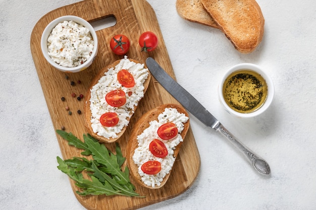 Bruschetta italiana con pomodori arrostiti, mozzarella ed erbe su un tagliere.