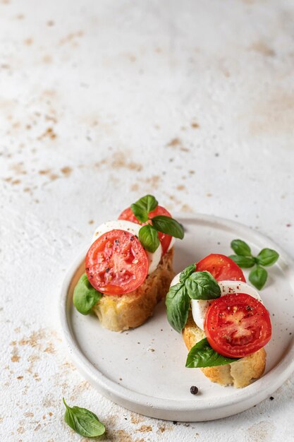 Bruschetta italiana con pomodori mozzarella e basilico su piatto bianco con spazio di testo