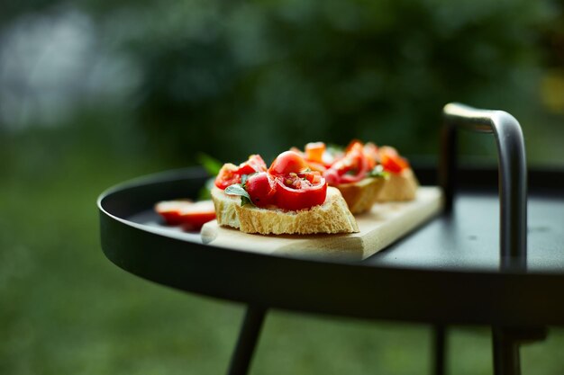 Bruschetta italiana con pomodori rossi freschi ed erbe di basilico su una tavola di legno all'aperto