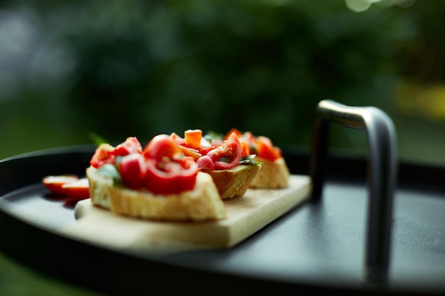 Bruschetta italiana con pomodori rossi freschi ed erbe di basilico su una tavola di legno all'aperto