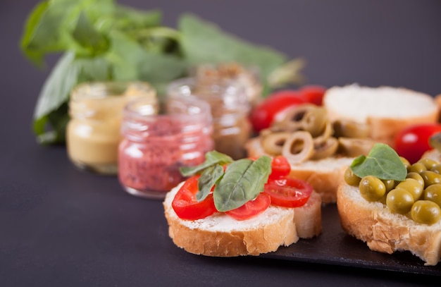 Bruschetta italiana in assortimento sul piatto, con una piccola bottiglia di senape