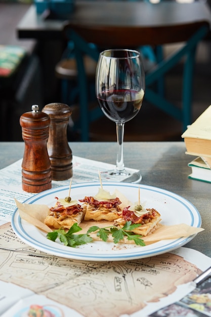 Bruschetta su un tavolo di legno in un piatto bianco e un bicchiere di vino rosso