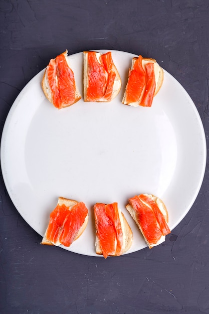 Bruschette con caviale e burro di trota su un piatto bianco su una superficie grigia