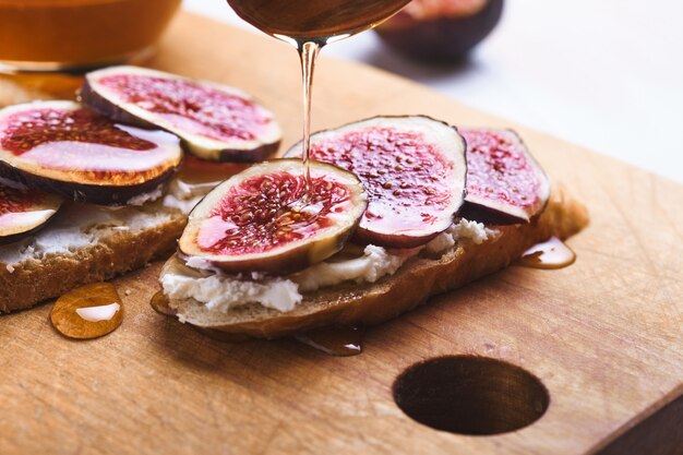 Bruschette con fichi, formaggio a pasta molle e miele su una tavola di legno.