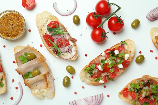 Bruschette e ingredienti italiani deliziosi degli spuntini su fondo bianco