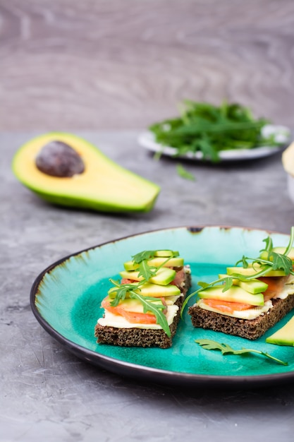 Bruschette pronte da mangiare con salmone, burro, avocado e rucola su un piatto