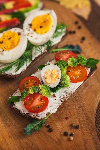 Bruschette su pane scuro con ricotta uova verdure spezie ed erbe aromatiche su una tavola di legno