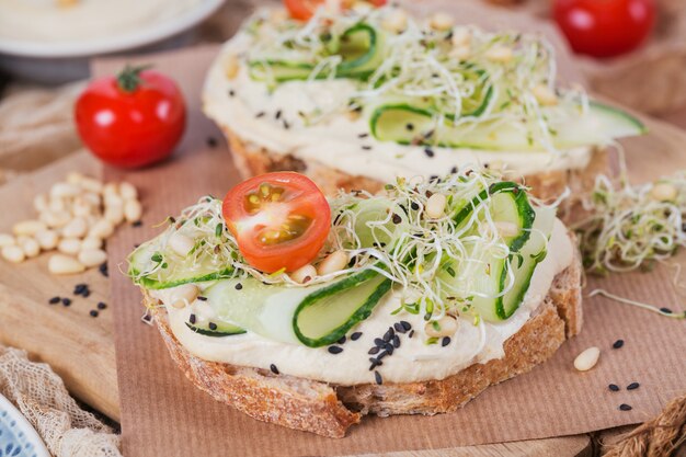 Bruschette vegetariane sane con pane, hummus, pomodorini, cetrioli e pinoli