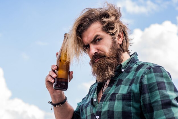 Brutale hipster caucasico con la barba in camicia bere birra o acqua, alcol.