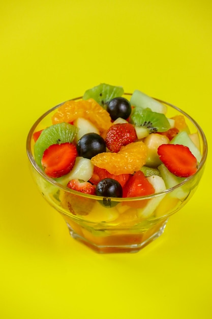 Buah di insalata Deliziosa macedonia con frutta fresca sana in una ciotola sul primo piano del tavolo