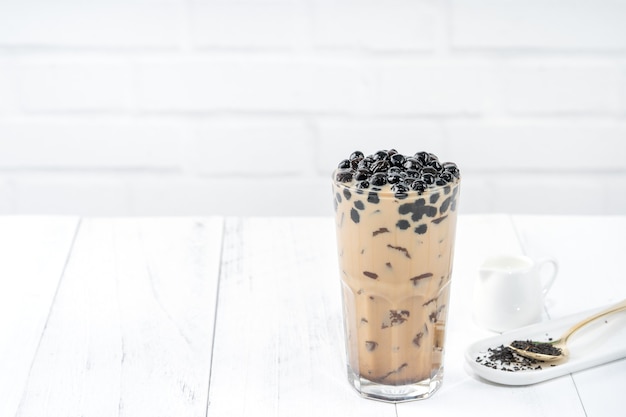 Bubble tea al latte con guarnizione di perle di tapioca, famosa bevanda taiwanese sul tavolo di legno bianco