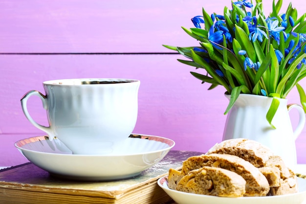 Bucaneve in un vaso, una tazza di tè e biscotti in tavola