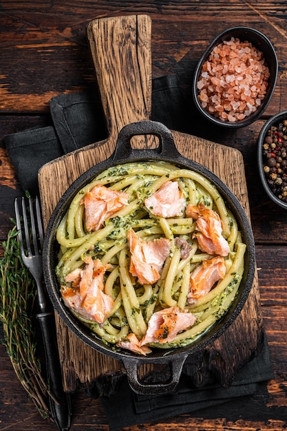 Bucatini al salmone con crema di spinaci e filetto di pesce. Fondo in legno. Vista dall'alto.