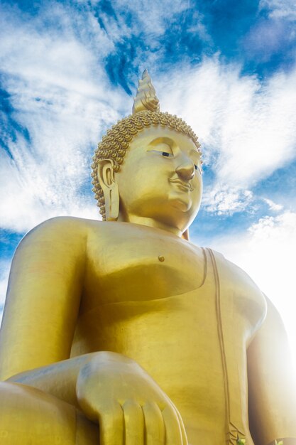 Buddha dorato della statua sul fondo del cielo blu in Tailandia.