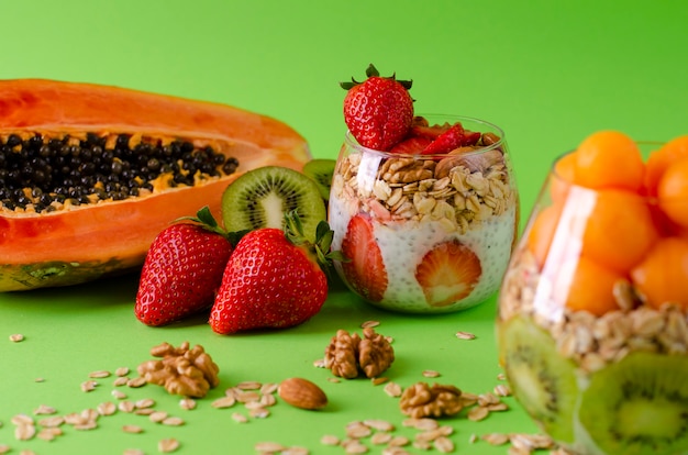 Budini di Chia con frutta fresca cruda tropicale con fiocchi d&#39;avena e noci per mangiare sano sul verde