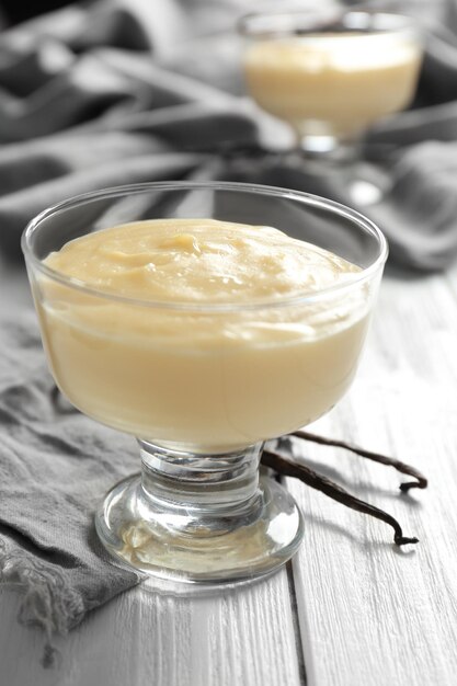 Budino alla vaniglia in ciotola da dessert di vetro sulla tavola di legno