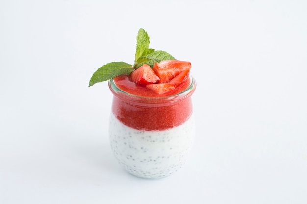 Budino con semi di chia e fragola nel barattolo di vetro su fondo bianco. Copia spazio. Avvicinamento.