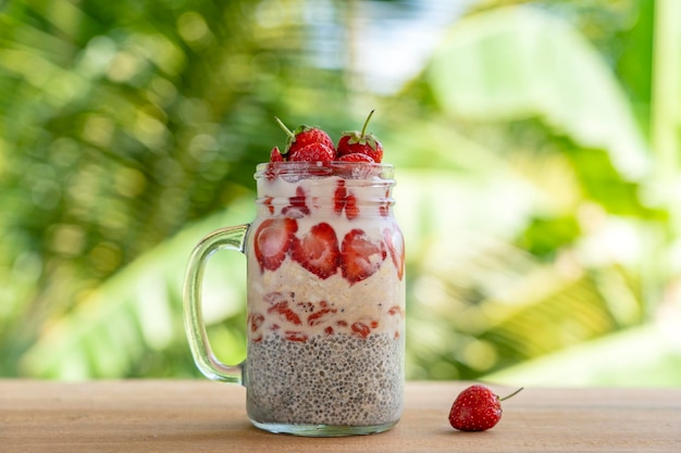 Budino di chia al latte di mandorla con fragole rosse fresche Bacche di goji e fiocchi di avena in un vasetto di vetro Tazza Colazione vegana crudista Semi di chia e frutta fresca e frutti di bosco Dessert