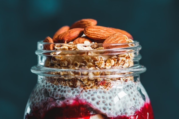 Budino di chia biologico con marmellata di banane muesli e mandorle su sfondo blu scuro Il concetto di cibo sano