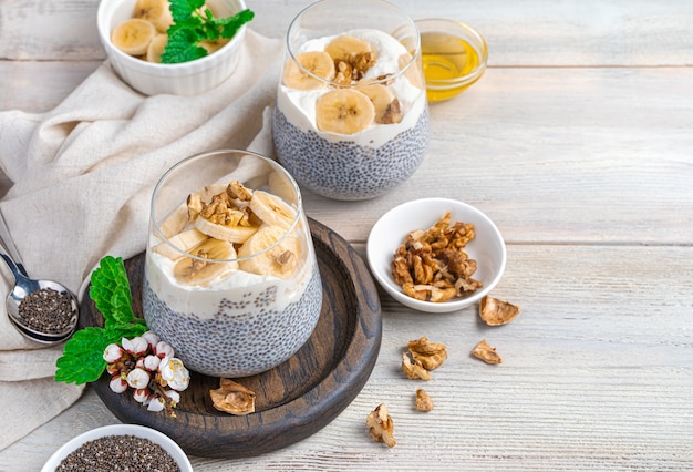 Budino di Chia con banana, noci e miele su una parete beige con spazio da copiare. Una colazione sana e ricca di vitamine. Il concetto di dieta e alimentazione sana.