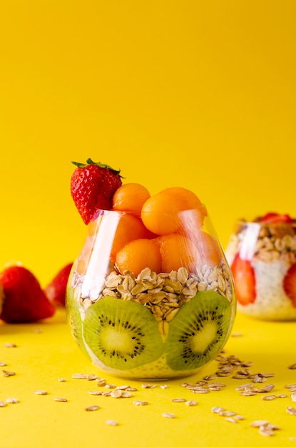 Budino di Chia con kiwi, fiocchi d&#39;avena e palline di melone o papaia in un bicchiere giallo