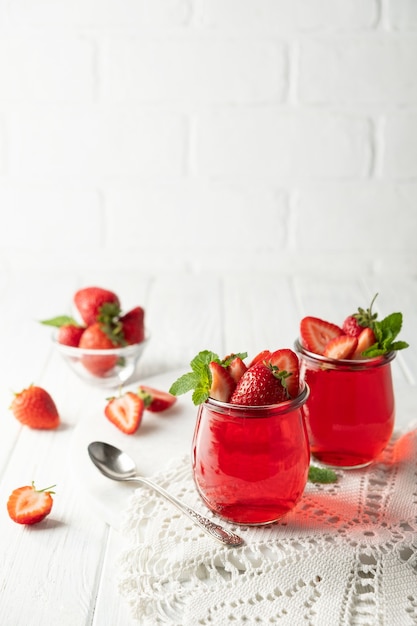 Budino di gelatina dolce dessert con fragole in un barattolo di vetro su sfondo bianco