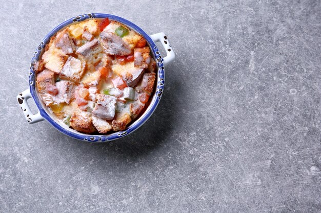 Budino di pane appena sfornato in casseruola su sfondo grigio