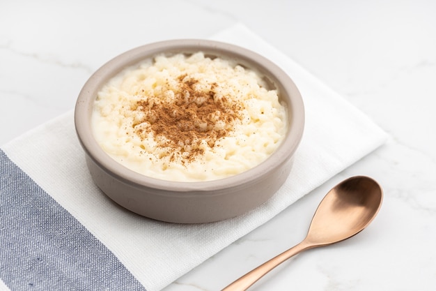 Budino di riso cremoso con cannella in una ciotola sul tavolo di marmo bianco. Dolce tipico spagnolo