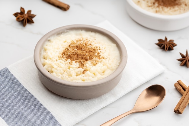 Budino di riso cremoso con cannella in una ciotola sul tavolo di marmo bianco. Dolce tipico spagnolo