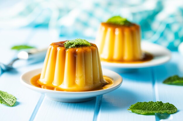 Budino dolce alla vaniglia Dessert dolce con caramello su tavola blu