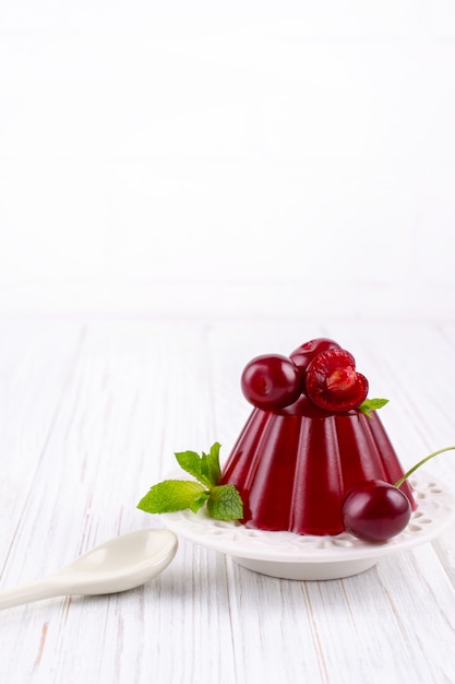 Budino dolce della gelatina del dessert con la ciliegia sul piatto bianco