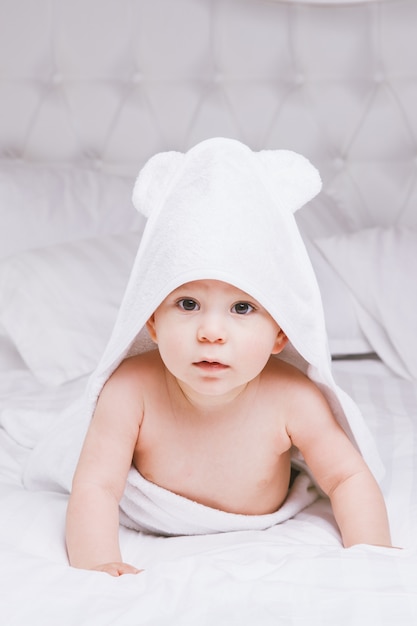 Bugia adorabile del bambino sull&#39;asciugamano bianco a letto. Infanzia felice e concetto di assistenza sanitaria.