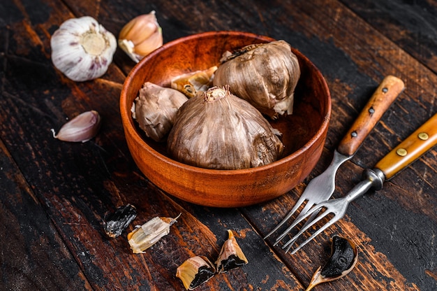 Bulbi e spicchi di aglio nero fermentato in un piatto