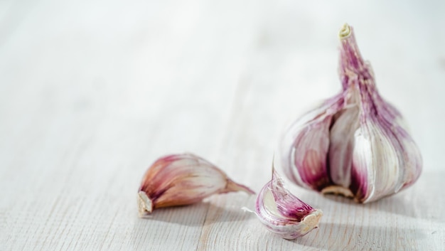 Bulbo d'aglio con spicchi d'aglio su sfondo bianco di legno Aglio perfetto con spazio di copia per testo o disegno Orizzontale