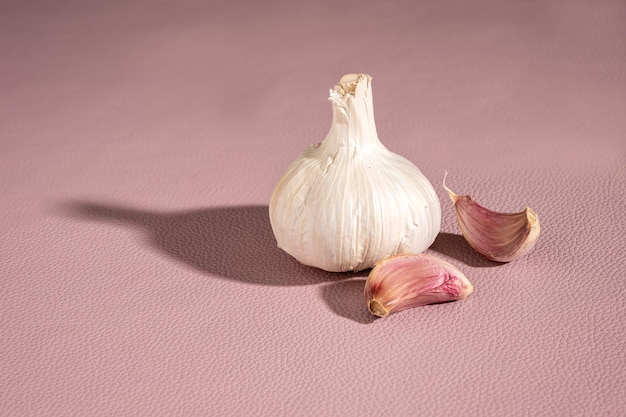 Bulbo d'aglio viola e chiodi di garofano su sfondo rosa
