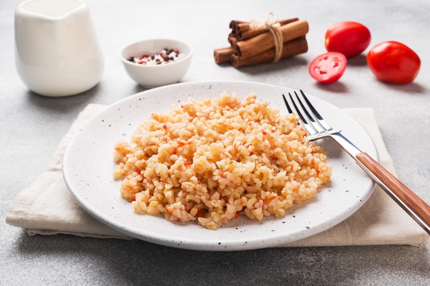 Bulgur bollito con i pomodori in un piatto di ceramica.