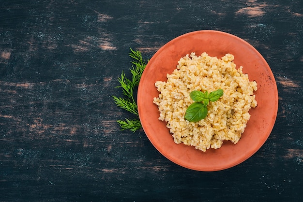 Bulgur con basilico su un piatto Su uno sfondo di legno Vista dall'alto Spazio di copia