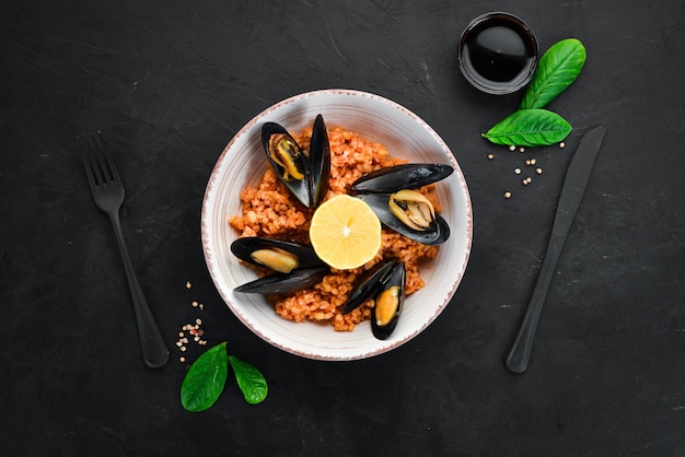 Bulgur con cozze e salsa di pomodoro in un piatto Sullo sfondo vecchio Vista dall'alto Spazio libero per il testo