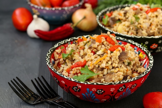 Bulgur con funghi e verdure in ciotole su oscurità