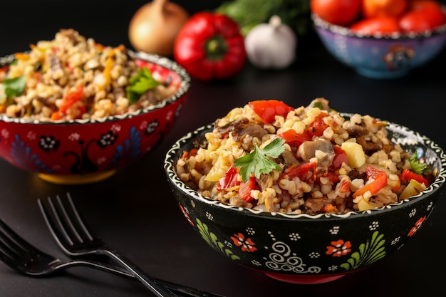 Bulgur con funghi e verdure in due ciotole su uno sfondo scuro