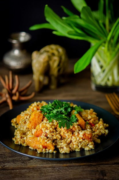 Bulgur con zucca su un tavolo di legno. Ricette vegetariane della cucina indiana.